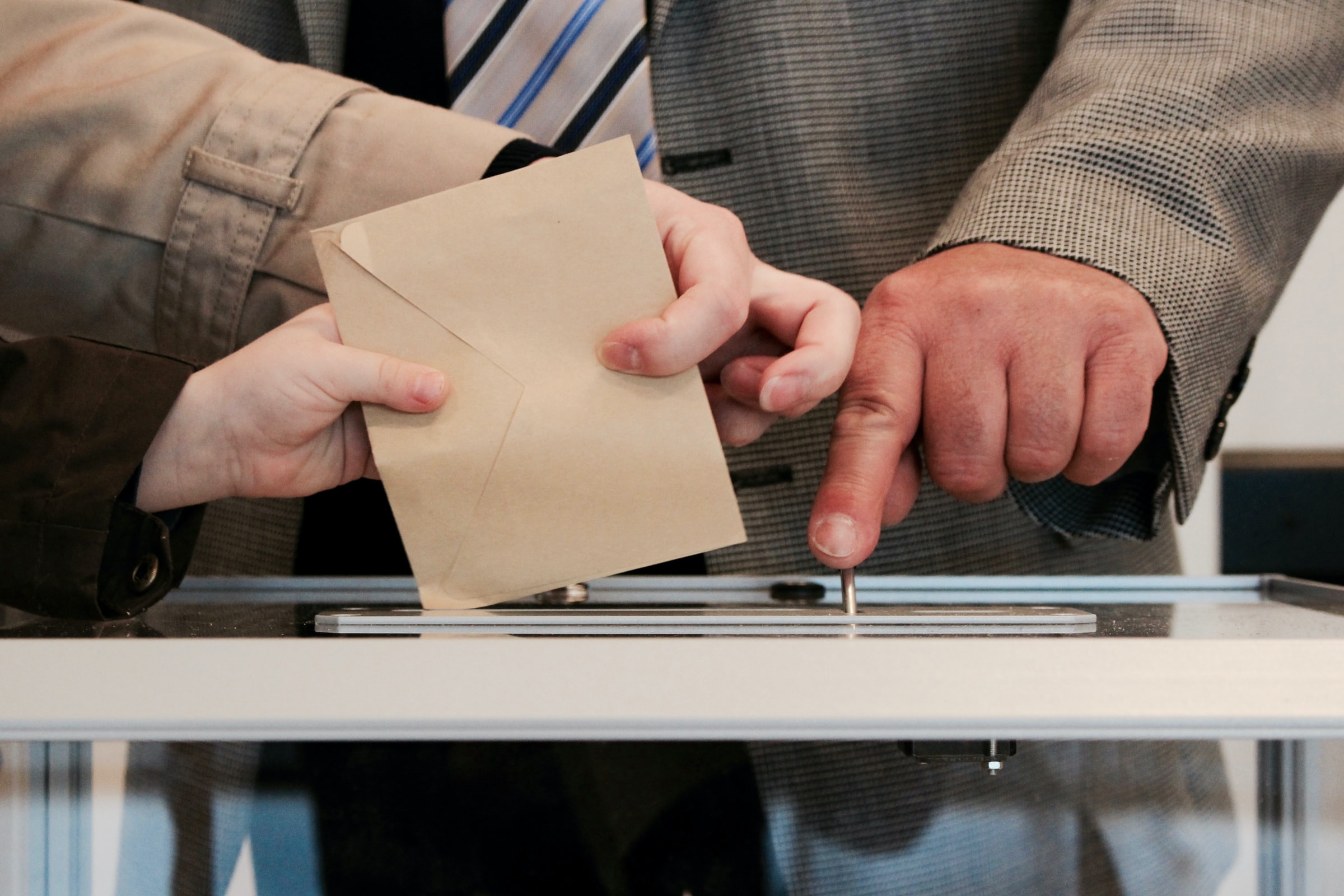 Wahlumschlag wird in Wahlurne eingegeben, Wahlhelfer kontorlliert